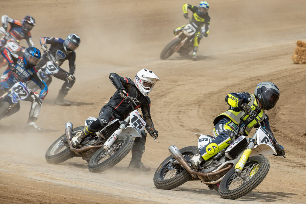 موتورسوار در مسابقات Flat Track در حال پیچیدن روی زمین خاکی با زاویه بالا و لغزش کنترل‌شده لاستیک عقب