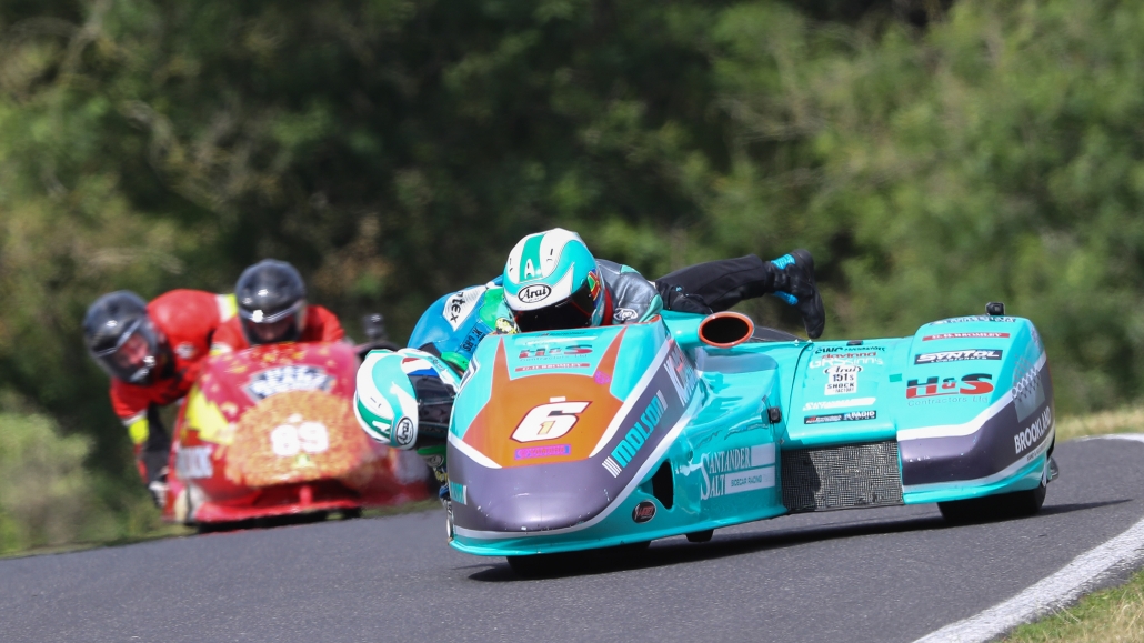 موتورسیکلت سایدکار در حال پیچیدن در پیست مسابقه — راننده و کمک‌راننده در هماهنگی کامل برای حفظ تعادل در مسابقه Sidecar Racing