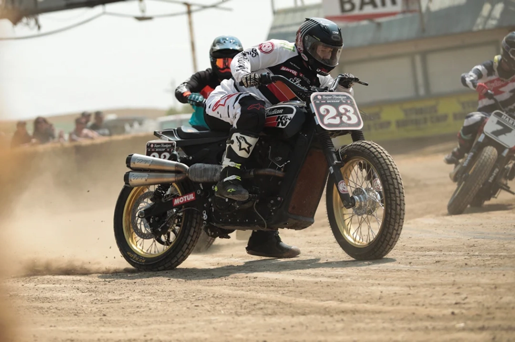 موتورسوار کلاس Super Hooligan در مسابقه روی پیست خاکی با موتورسیکلتی سبک و شماره 23 در حال عبور از پیچ